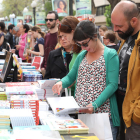 Diverses persones fullegen llibres durant la Diada de Sant Jordi a la Rambla Nova de Tarragona.