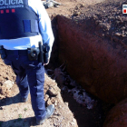 Un agent comprovant l'aparició de cadàver d'ovelles en fosses properes a l'explotació agrària del propietari que ha estat denunciat.