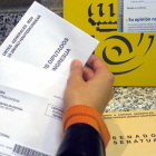 Imatge d'arxiu en la qual una ciutadana deposita el seu vot per correu en una oficina postal.