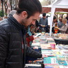 Un home remena una parada de llibres a la Rambla Nova de Tarragona, durant la diada de Sant Jordi. Foto del 23 d'abril del 2019 (Vertical).