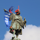 La estatua de Colón con dos activistas descolgando una pancarta.