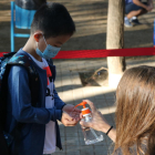 L'alumne d'una escola de Barcelona rebent gel desinfectant a l'entrada del centre.