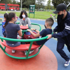 Un grupo de niños, protegidos por mascarillas, juega en un parque.