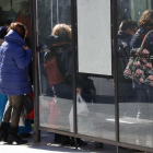 Gent protegint-se del vent, en una parada d'autobús a Valls.