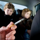 Un conductor fumant amb dos nens al darrera.