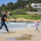 Un pare jugant i corrent amb la seva filla per la sorra de la platja de l'Arrabassada, espai escollit per moltes famílies per passejar i sortir una estona.