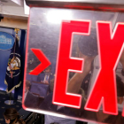Un cartell amb el missatge 'Exit' (Sortida) en primer pla, amb la imatge de Trump en un dels costats, durant un discurs a la Casa Blanca.