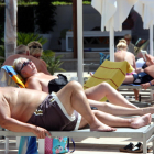 Una pareja de turistas extranjeros tomando el sol en unas vagas en un resorte de Cambrils.
