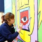 La ilustradora Cristina Daura mientras pinta un mural en el marco de la campaña 'Tolerancia Cero' de FGC