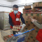 Dos voluntaris de Creu Roja Tarragona omplint el carro d'aliments per una persona en situació de vulnerabilitat
