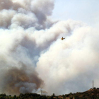 Una hidroavión sobrevuela una gran nube de humo de un incendio forestal en la Ribera d'Ebre el 26 de junio del 2019.