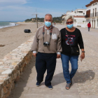 Una pareja de personas mayores con mascarilla caminando por el paseo marítimo de Altafulla.