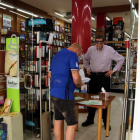 Pla general d'un client a l'entrada de la llibreria La Capona comprant un llibre escolar