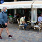 Pla general de la terrassa d'una cafeteria a Calafell Platja mentre un home passeja amb mascareta.