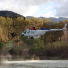 Plano general de un helicóptero vaciando la carga de insecticida biológico BTI en el río Ebro, a la altura del azud de Xerta (Baix Ebre), contra la mosca negra.