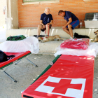 Diverses persones desallotjades, al pati de l'escola de Flix, amb diverses lliteres de la Creu Roja en primer terme.