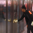 Una trabajadora del Mercado Central de Tarragona limpiando los pulsadores y las puertas de los ascensores.