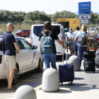 Pla general de turistes amb maletes, esperant agafar un taxi a l'aeroport de Reus, després d'aterrar amb el primer avió que arriba a la capital del Baix Camp des de l'alarma, provinent del Regne Unit.