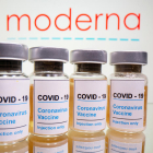 Viales con un adhesivo que dice «COVID-19 / Vacuna contra el coronavirus / sólo por inyección' y una jeringa ante el logotipo de Moderna en