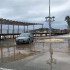 Un coche intentando pasar por una rotonda con charcos de agua de mar, en la playa de la Arrabassada de Tarragona, a causa del temporal.