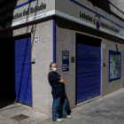 Un ciutadà transita enfront de l'edifici d'una administració de loteria al carrer de la Mar de Badalona (Barcelona)