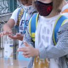 Dos alumnos de primaria lavándose las manos con hielo|gel hidroalcohòlic en el acceso de la escuela Sant Llàtzer de Tortosa.