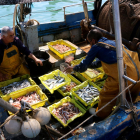 Dos pescadores de Tarragona acabando de escoger y clasificar el pescado encima de la barca, en el Serrallo.