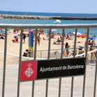 Plano abierto de la playa Nova Icària de Barcelona con una valla en primero plano.