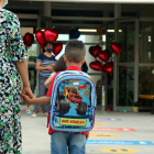 Un niño de la mano de su madre llegando a una escuela.