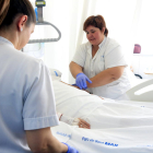Dues infermeres, atenent una persona malalta ingressada en un hospital.