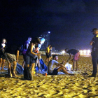 Un grupo de personas que hacía botellón en la playa de la Barceloneta ante la presencia de la Guardia Urbana.