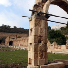 Un arc del claustre major de la Cartoixa d'Escaladei en primer terme, amb el pati al darrer i, al fons, la silueta del Montsant.