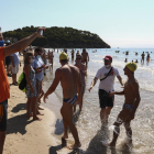 Uns nedadors són rebuts a l'arribada a la meta situada a la platja de la Móra.
