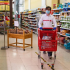 Un voluntari de la Creu Roja fa la compra en un supermercat.