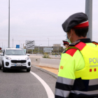 Un agente de los Mossos de Esquadra en primer término y un vehículo en el control policial de la T-11 en Tarragona.