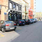 Pla general del carrer on van passar els fets amb els bars al costat i alguns cotxes aparcats.