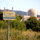 Un cartell amb el nom d'un carrer a l'Ametlla de Mar (Baix Ebre) amb la central nuclear de Vandellòs (Baix Camp), desenfocada, al fons.