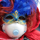 Una persona con la máscara de Carnaval y una mascarilla de papel por el coronavirus en Venecia