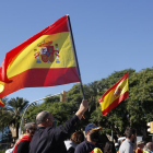 Unos manifestantes alzando banderas españolas durante la concentración en el monumento a Cristòfor Colom
