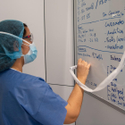 Una professional sanitària pren notes en una pissarra dels tractaments i proves als pacients amb covid-19 en un dels blocs quirúrgics de l'Hospital Clínic de Barcelona habilitat com a UCI en la pandèmia de coronavirus.