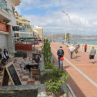 Diverses persones disfrutande un cafè en una terrassa mentre unes altres caminen pel passeig de la platja de les Pedreres, a Las Palmas de Gran Canaria.