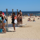 Diverses persones a les dutxes, a la platja de Sant Miquel, a Barcelona