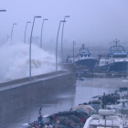 Una gran onada batent contra el moll del port de l'Ampolla amb les barques de pesca amarrades a l'interior.