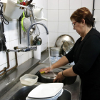 Pla general d'una dona de Castellolí mentre frega els plats amb l'aigua de l'aixeta.
