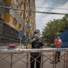 Una persona de seguretat vigila un complex residencial tancat prop del mercat de Yuquandong, al districte de Haidian, Pequín.