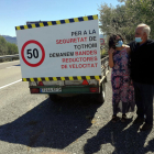 Dos de los vecinos de la nueva plataforma de Ascó al lado del cartel reivindicativo para pedir mejoras en seguridad viaria en la C-12.