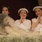 Plano medio de tres niñas vestidas de comunión durante la Coronación del Señor en Reus, delante del Cristo Ry..