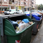 Plano abierto de una isla de contenedores de la calle de Cambrils de Reus, con un contenedor de rechazo lleno de basura en primer término.