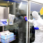 Una profesional sanitaria limpiando los cristales de una UCI con pacientes con covid-19 en el Hospital del Mar, en la pandemia de coronavirus.