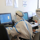 Dos médicos con el equipo de protección individual por el coronavirus consultando información de pacientes con covid-19 en el ordenador, en el Hospital del Mar.